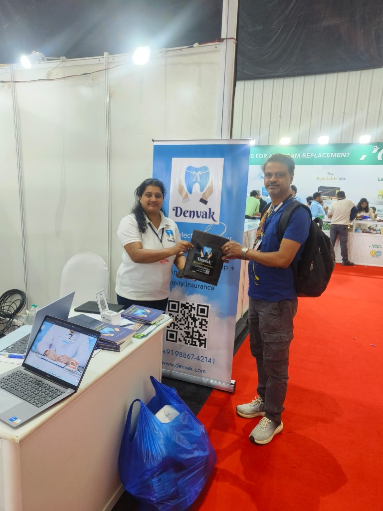 Denvak representative handing a kit to a dental delegate at Expodent Bengaluru